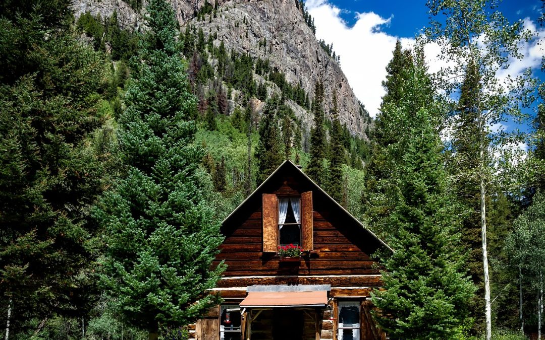 log cabin in front of steep mountain face in colorado summer