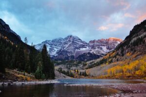 lake in foreground with autumn aspens in midground and snowy mountains in the background